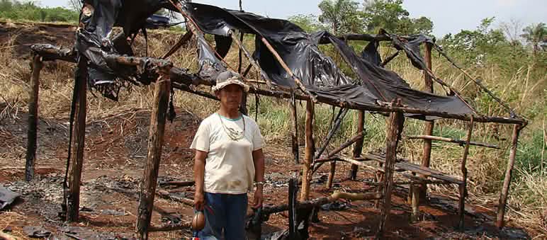 A Guarani woman infront of a burnt down hut