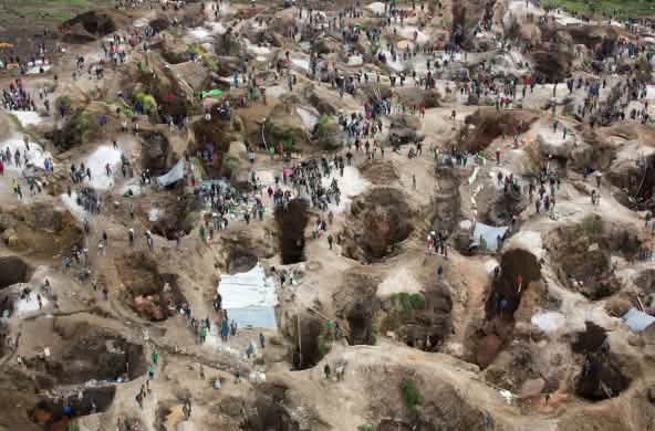 Deep holes, some filled with water, with many people in between. View from above