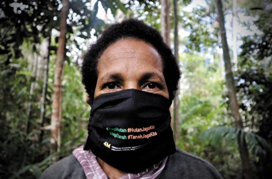 Papuan woman wearing a mask with the slogan “Protect the forest – the forest protects us”