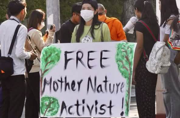 Young woman holding a large placard with the text “Free Mother Nature Activist!”