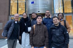 Group photo of seven people in front of the entrance of a building of the EU Commission in Brussels