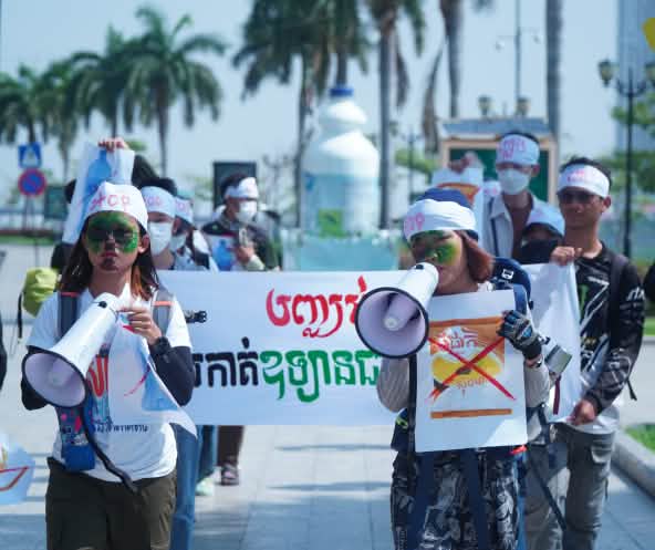 A group of young students walks through a street with megaphones and banners