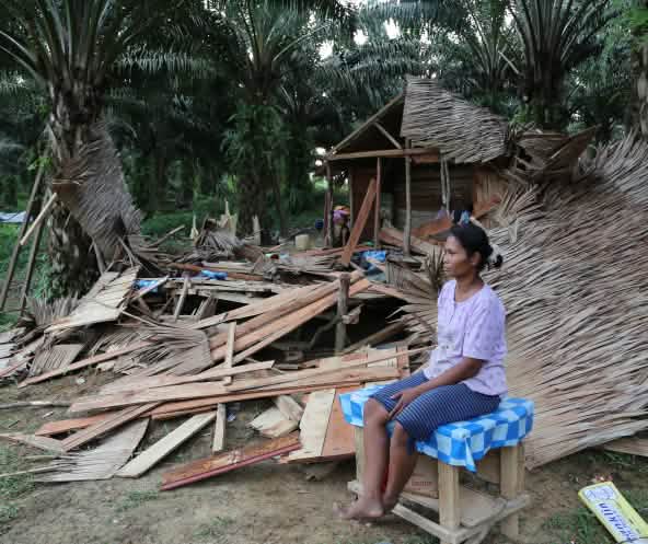 A villager sitting in front of the ruins of her house