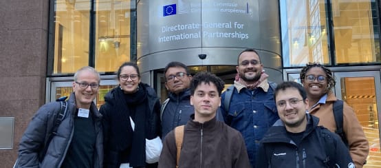 Group photo of seven people in front of the entrance of a building of the EU Commission in Brussels