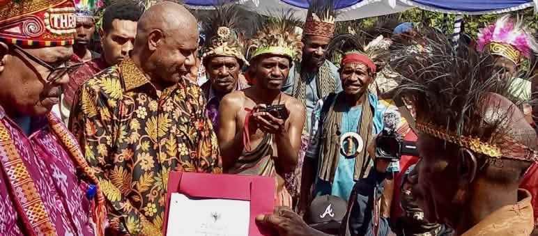 Presenting the certificate of recognition for the Indigenous community and ancestral forest A group of Papuans in traditional clothing holding a certificate