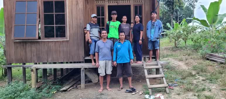 Locals welcome Rainforest Rescue’s visit Seven people in front of a wooden house
