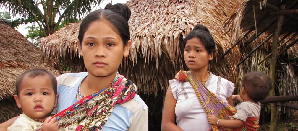 “The forest is our children's future. Oil palm plantations only make us poor.” Two women with their children in front of thatched houses