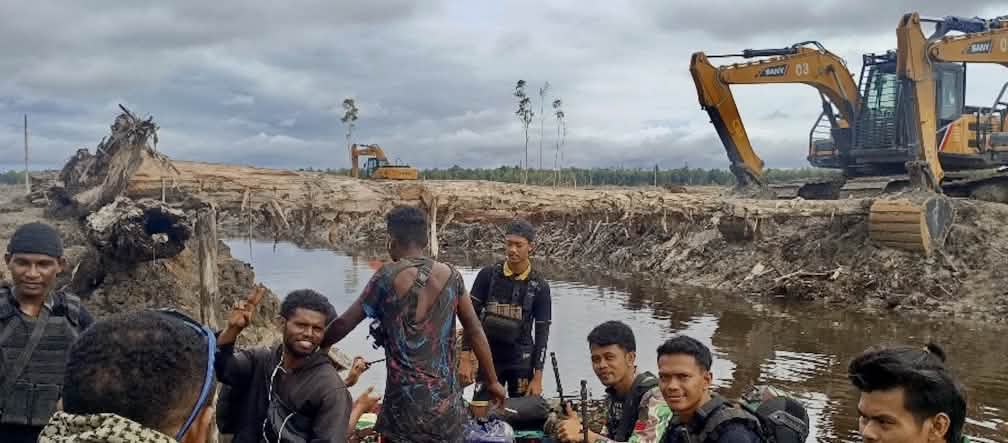 The clear-cutting has begun: Jhonlin Group excavators near Wanam village, March 2025 Excavators behind a group of men