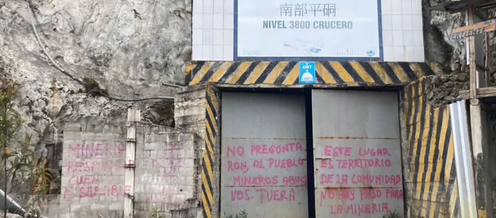 Gate to a mine tunnel with graffiti: “You didn't ask the people. Miners out. This is the territory of the village community. Mining will not be tolerated.” Closed entrance gate to a mine tunnel with protest graffiti