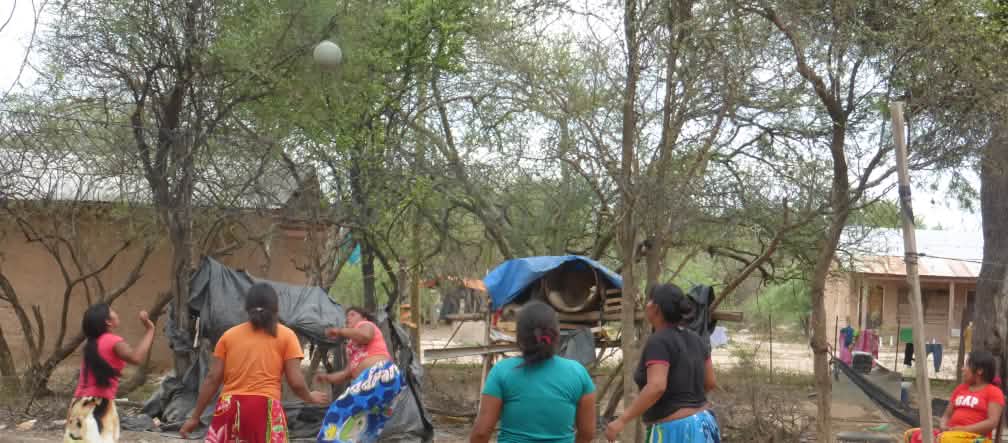 Manjui women in the settlement of Santa Rosa in the Chaco of Paraguay Five indigenous women play a ball game between trees and wooden houses
