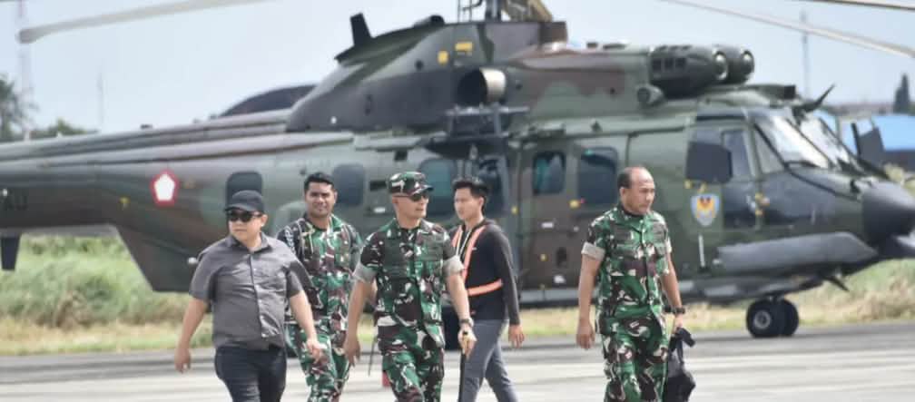 The military is protecting the sugar and bioethanol project in Merauke Three soldiers and two civilians walking in front of a helicopter