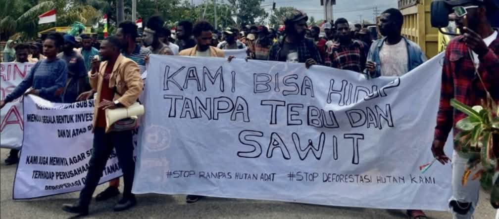 Protests against misguided agricultural projects: “We can live without sugar and palm oil!” Crowd with banner: “We can live without sugar and palm oil. Stop the theft of Indigenous land. Stop the destruction of our forest”