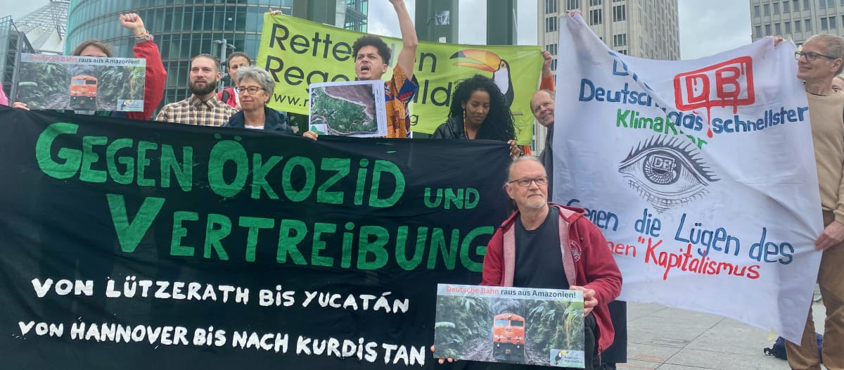 A group of people protesting with large, colorful banners in front of three office buildings