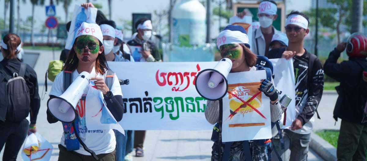 A group of young students walks through a street with megaphones and banners