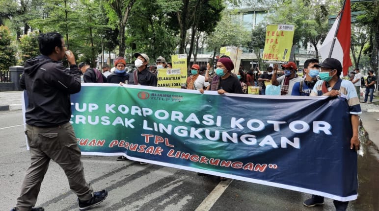 Photographer and protesters with a green banner