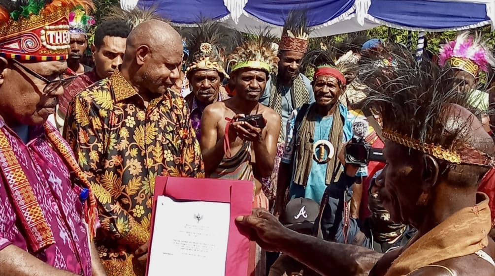 A group of Papuans in traditional clothing holding a certificate