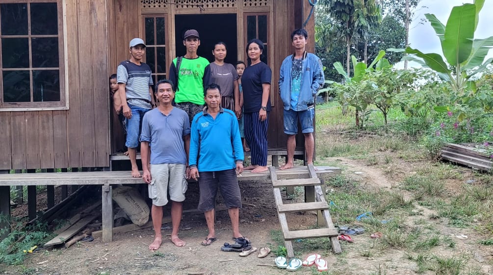 Seven people in front of a wooden house