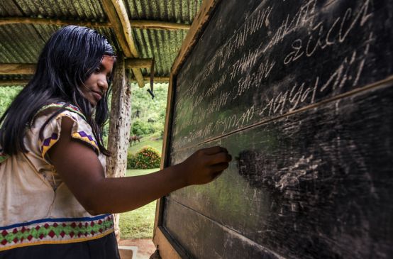 A young Ngäbe-Buglé woman writing on a blackboard