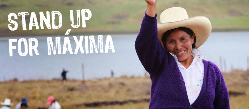 Máxima Acuña is standing firm in the face of violence and prison time. Maxima Acuña smiles and raises her right fist. Other farmers and the Blue Lagoon can be seen in the background.